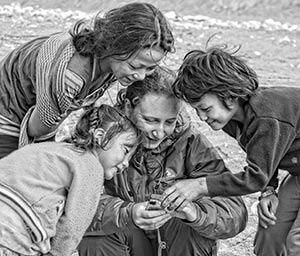 A black and white image of a woman surrounded by three interested children
